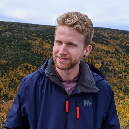 Alex MacLean looking slightly off to the left in front of a mountain