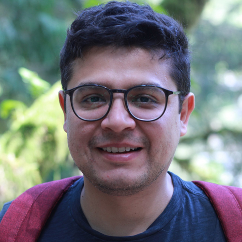 Luis Navarro del Angel looking at camera in front of greenery