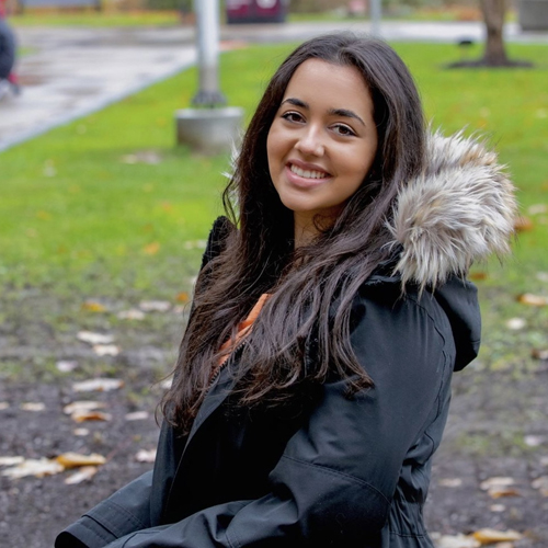 Shaden Ahmed sitting in a park, turned to the left and looking at the camera